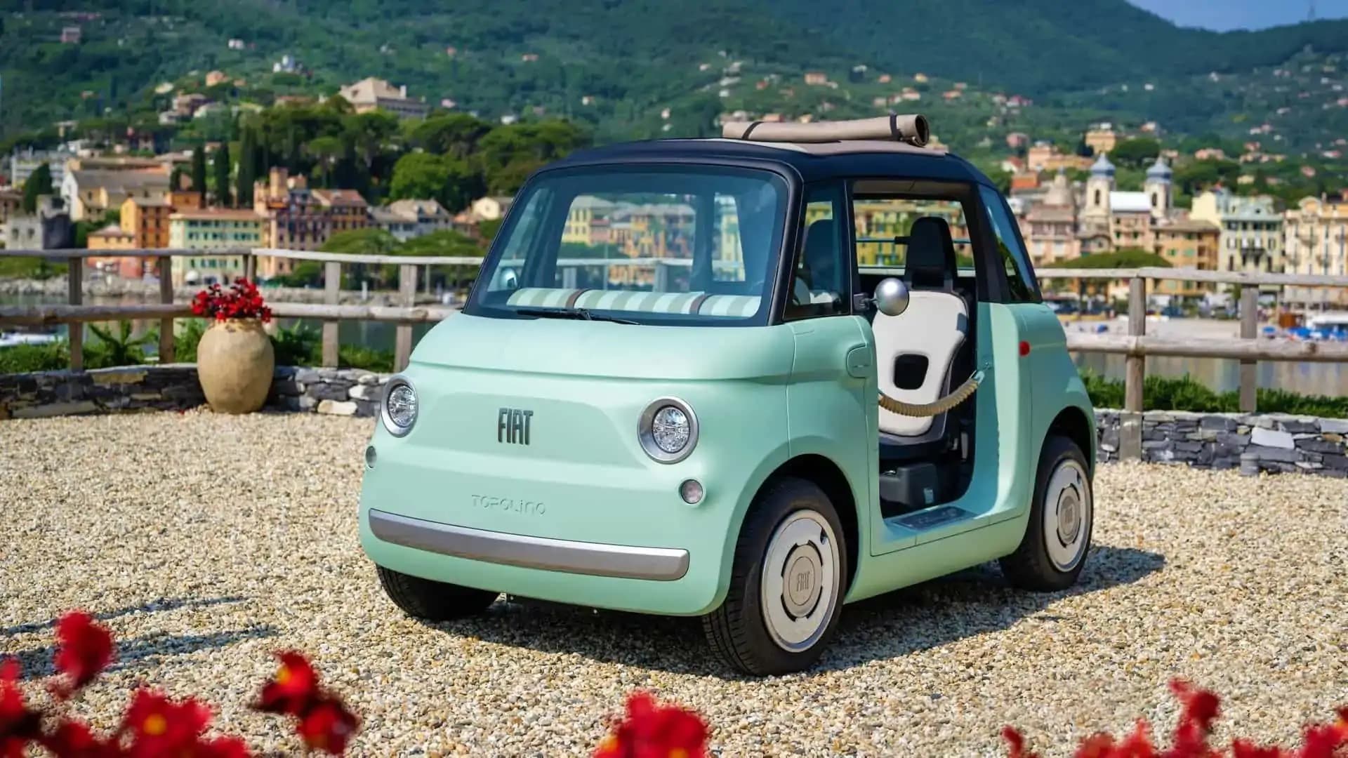 Fiat Topolino elétrico verde menta estacionado em calçada italiana com mar ao fundo